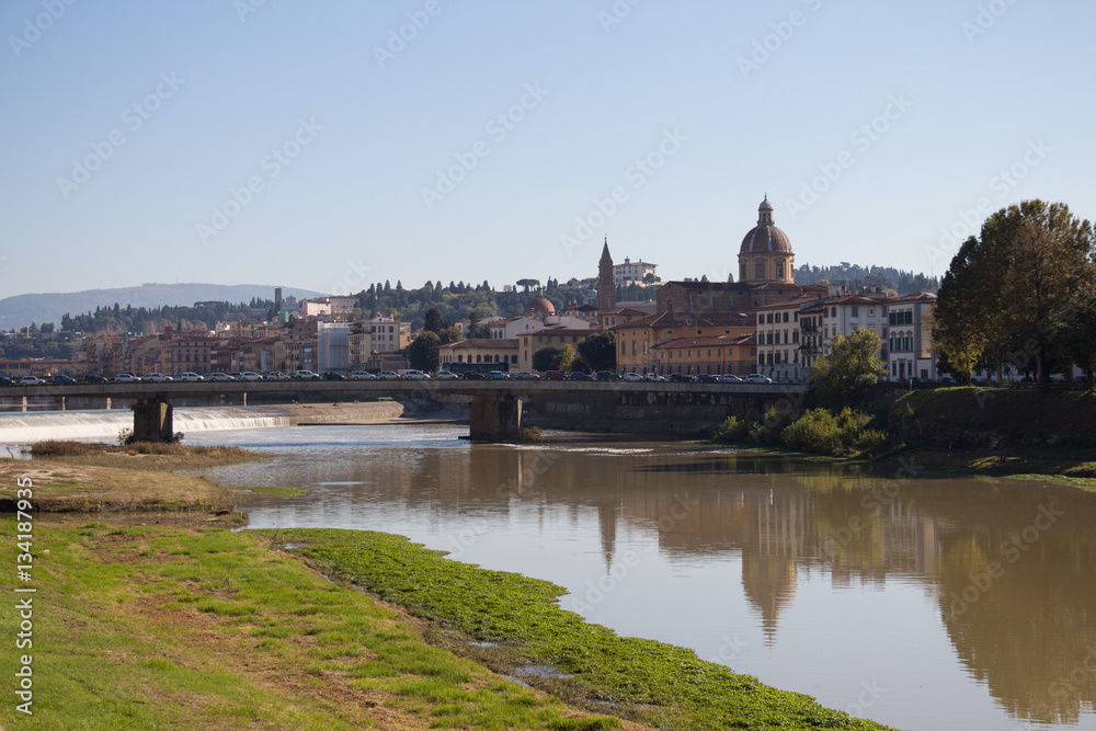 Arno River in a sunny day. Amerigo Vespucci Bridge and San Frediano church on background. Florence. Italy.