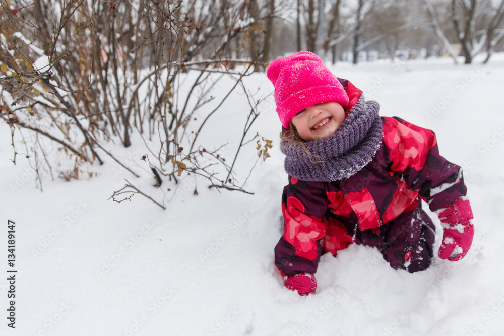 Small girl among winter bushes