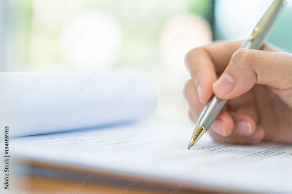 Hand with pen over application form . Hand with pen over application form .