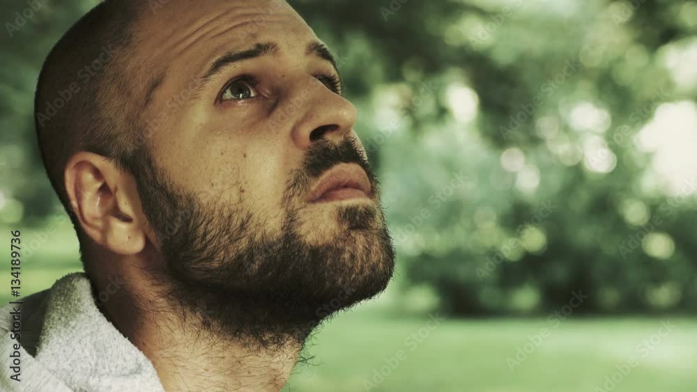 bald man alone in the park looks up at the sky to see if it would start to rain bald man alone in the park looks up at the sky to see if it would start to rain