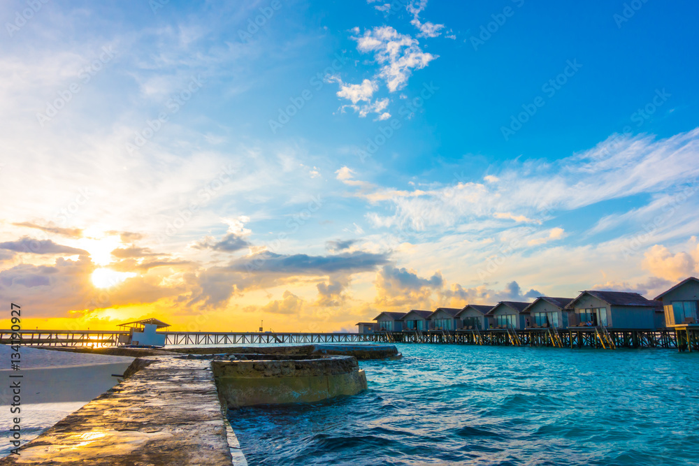 Beautiful sunrise with water villas in tropical Maldives islan Beautiful sunrise with water villas in tropical Maldives islan