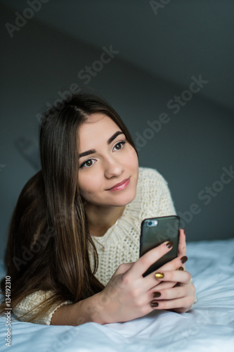Brunette girl with phone in her bed
