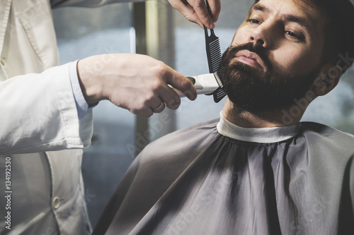 businessman’s beard being trimmed