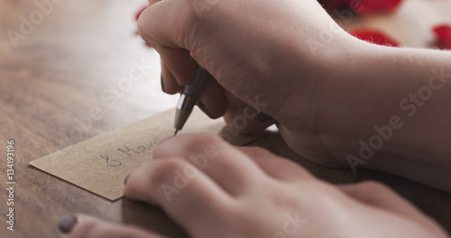 girl writes 8 march on a paper card on old wood background, 4k photo