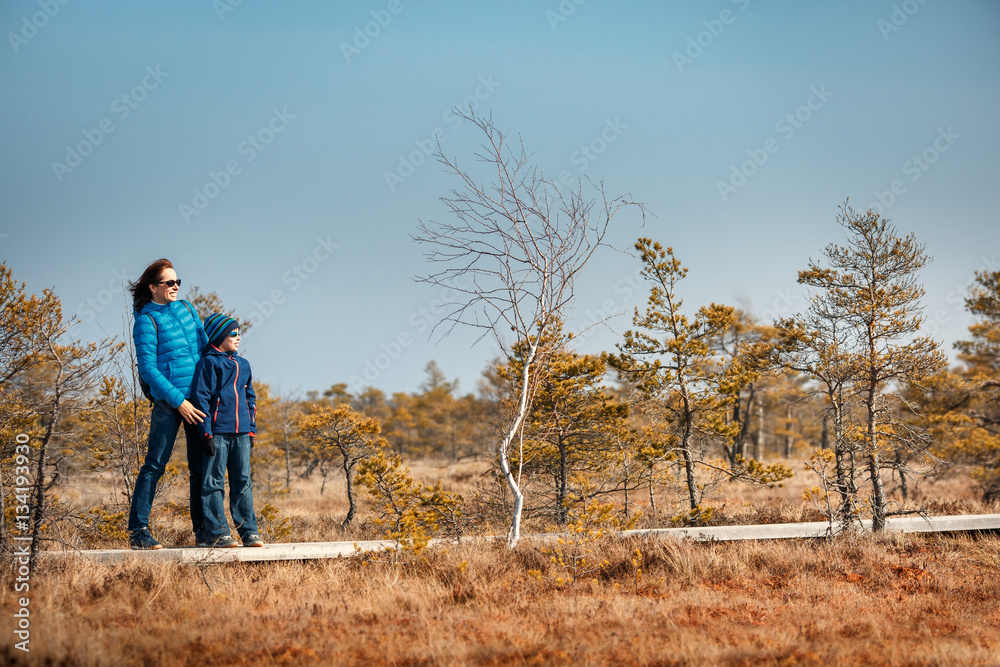 Cute little boy with mother walking on trail in swamp, Kemeri national park, Latvia