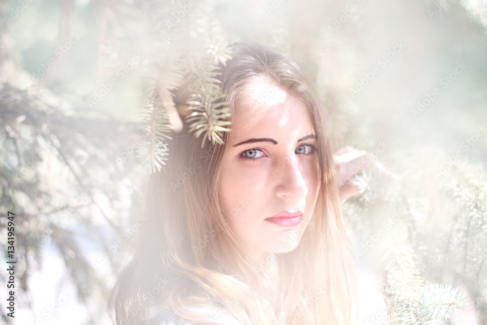 Portrait of a young woman in the spruce branches