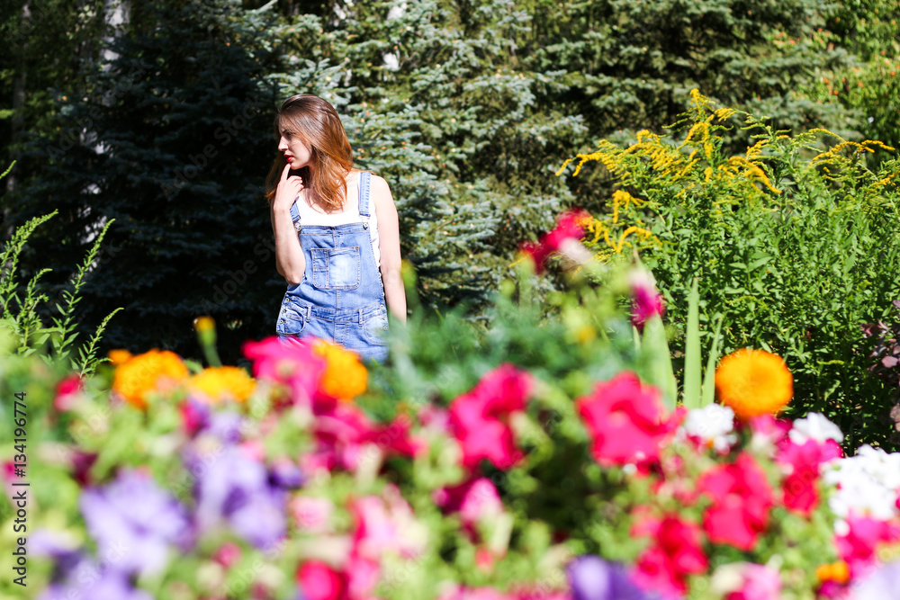 Young woman posing on the background, the foreground flowers Young woman posing on the background, the foreground flowers