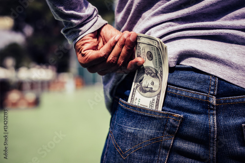 Man hand is putting money in the pocket.