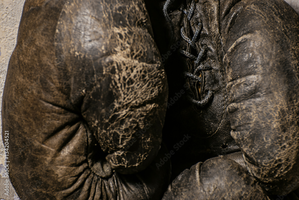 Naklejka premium old boxing gloves hang on nail on texture wall