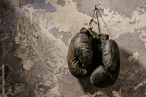 old boxing gloves hang on nail on texture wall © Vasilev Evgenii