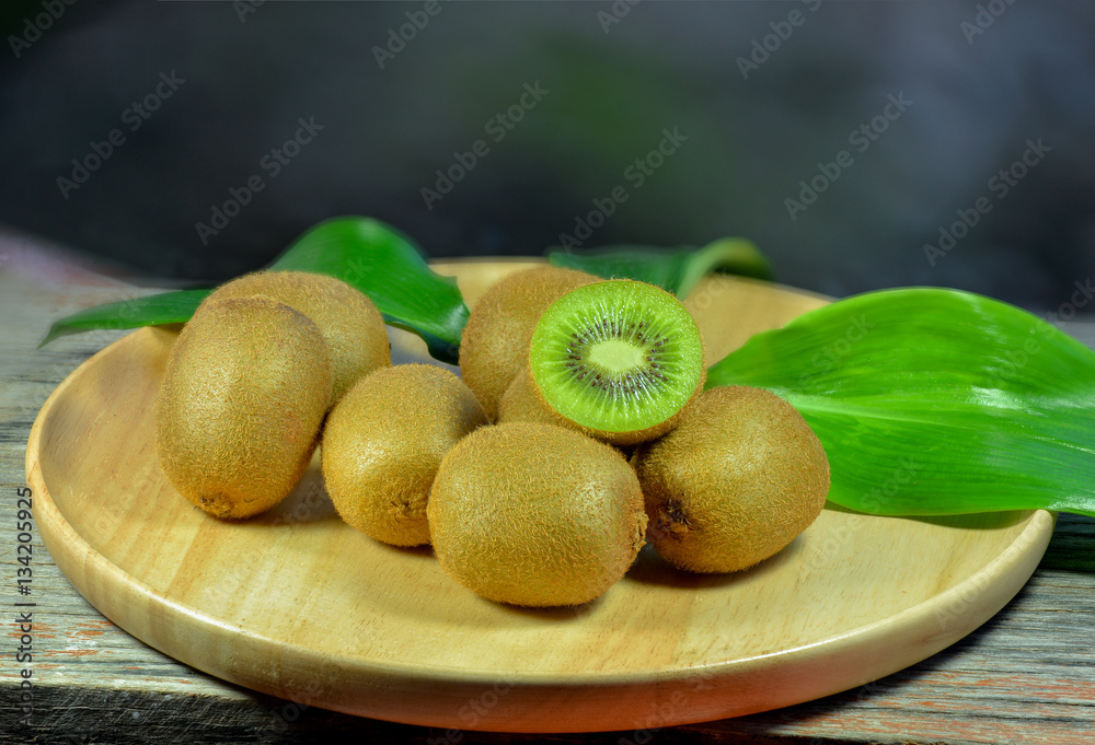 Kiwi fruit in a bowl on wooden background.