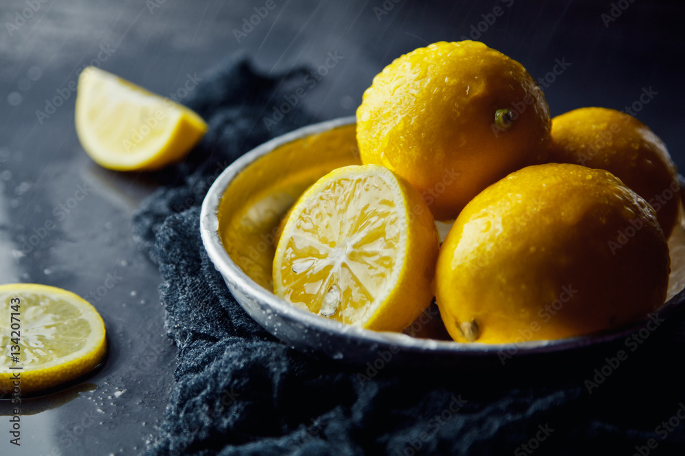 Beautiful ripe lemons in plate on a black background Beautiful ripe lemons in plate on a black background