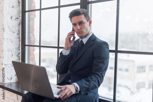 Young man talking on his mobile phone in office.