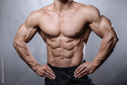 beautiful fitness male model posing in studio on white grey back