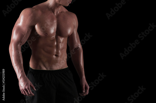 Muscular torso of male bodybuilder isolated. Cropped portrait of athlete with copy space on black background.
