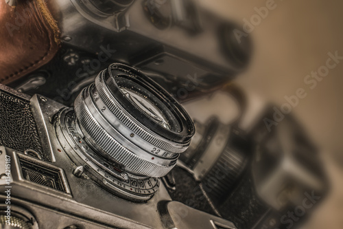 Close up view of old Russian analog film camera with vintage look. On the camera, there can be seen aperture ring, focusing ring, lens, filter thread. In background is another old camera with lens