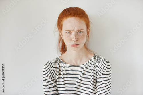 Canvas Print Pretty girl with ginger hair, gathered in ponytail pouting her lips, looking at