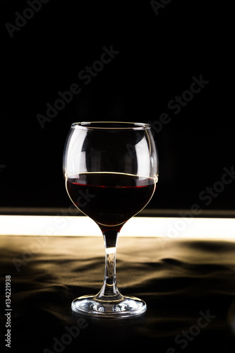 glass of red wine on a black background backlit