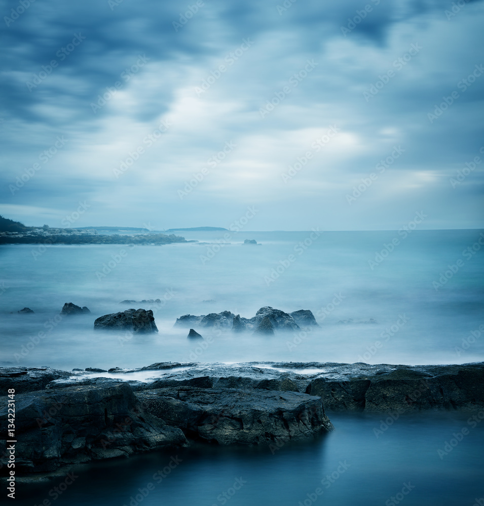 Peaceful Winter Seascape. Sea or Ocean with Dramatic Sky. Long Exposure. Calm Water and Moody Sky. Cold Mysterious Tranquility Concept. Blue Toned Photo with Copyspace.