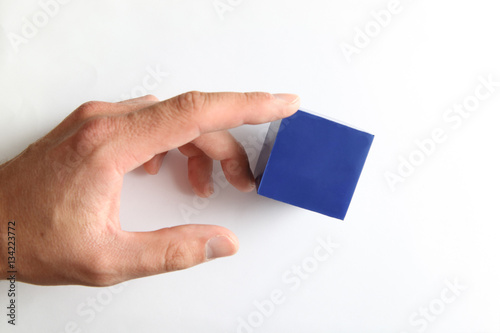 Hand touching small blue cube