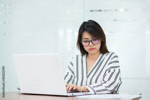 Happy beautiful young Asian woman smile while working with laptop