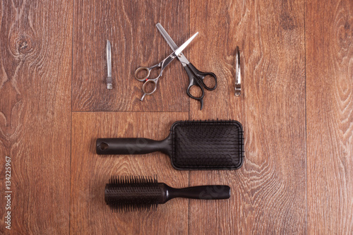 Set of combs, scissors and hair clips on the wooden background close up