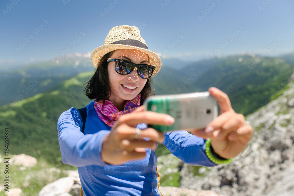 woman traveler in the mountains makes selfie on smartphone