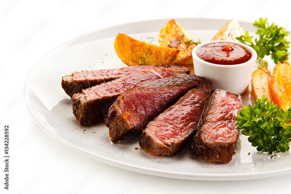Grilled steak, baked potatoes and grilled carrots on white background Grilled steak, baked potatoes and grilled carrots on white background