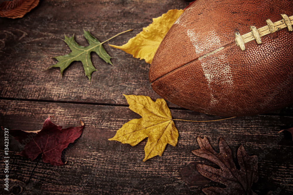 Obraz premium Old worn football with autumn leaves