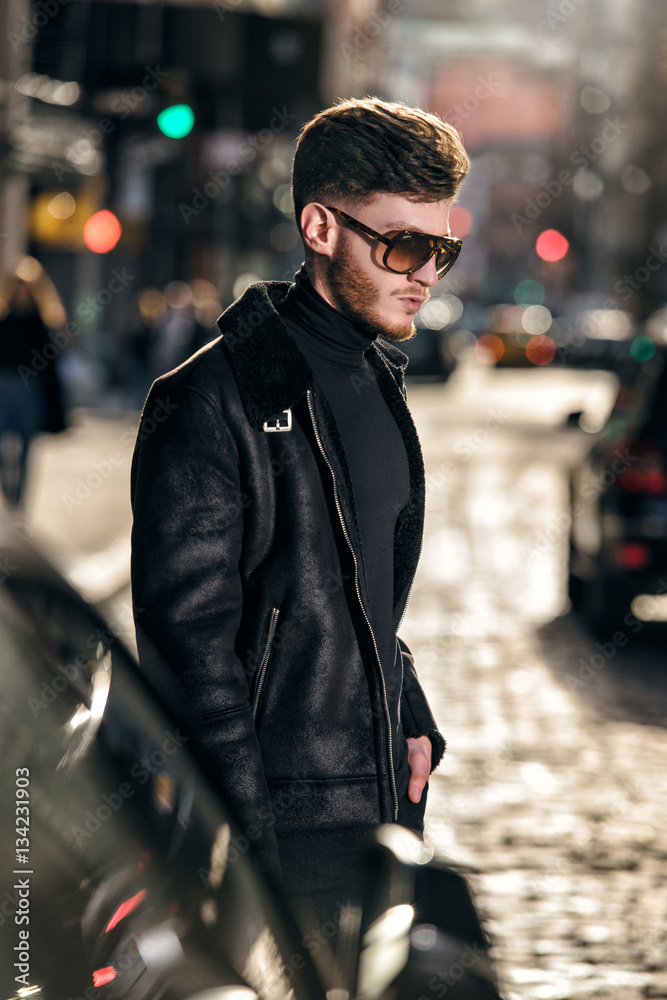 Handsome bearded man in leather jacket and sunglasses walking on city street. Handsome bearded man in leather jacket and sunglasses walking on city street.