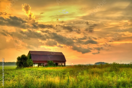 Wooden Barn Sunset. Rural sunset with an abandoned barn surrounded by farm fields. photo
