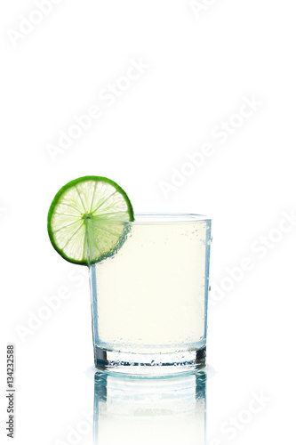 Glass of transparent beverage and lime slice