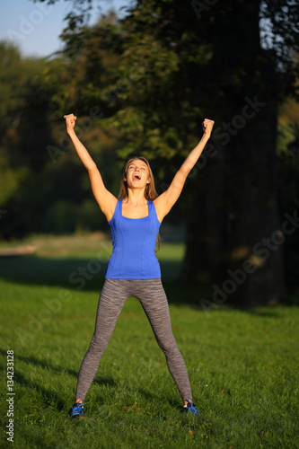 Girl screaming with joy in park lifted hands upwards