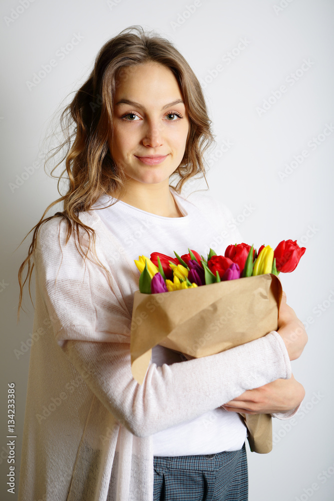 Young beautiful woman standing with a bouquet of colorful tulips Young beautiful woman standing with a bouquet of colorful tulips
