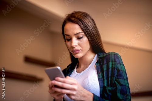Beautiful young woman typing a message on her smartphone. 