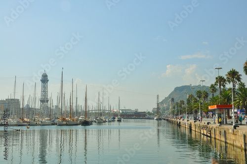 BARCELONA, SPAIN - SEPTEMBER 2016: Relax, travel, sea, sailing concept.Panorama on Barcelona Seaport with cruise yachts, funicular, Montjuic hill and people walking in embankment under palm trees.