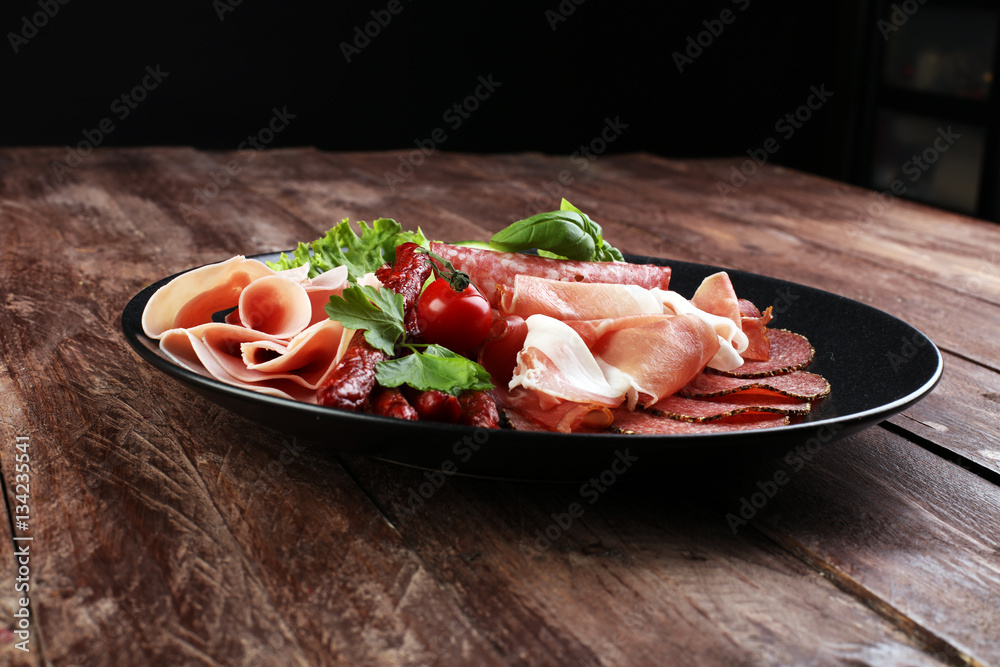 Food tray with delicious salami, pieces of sliced ham, sausage,