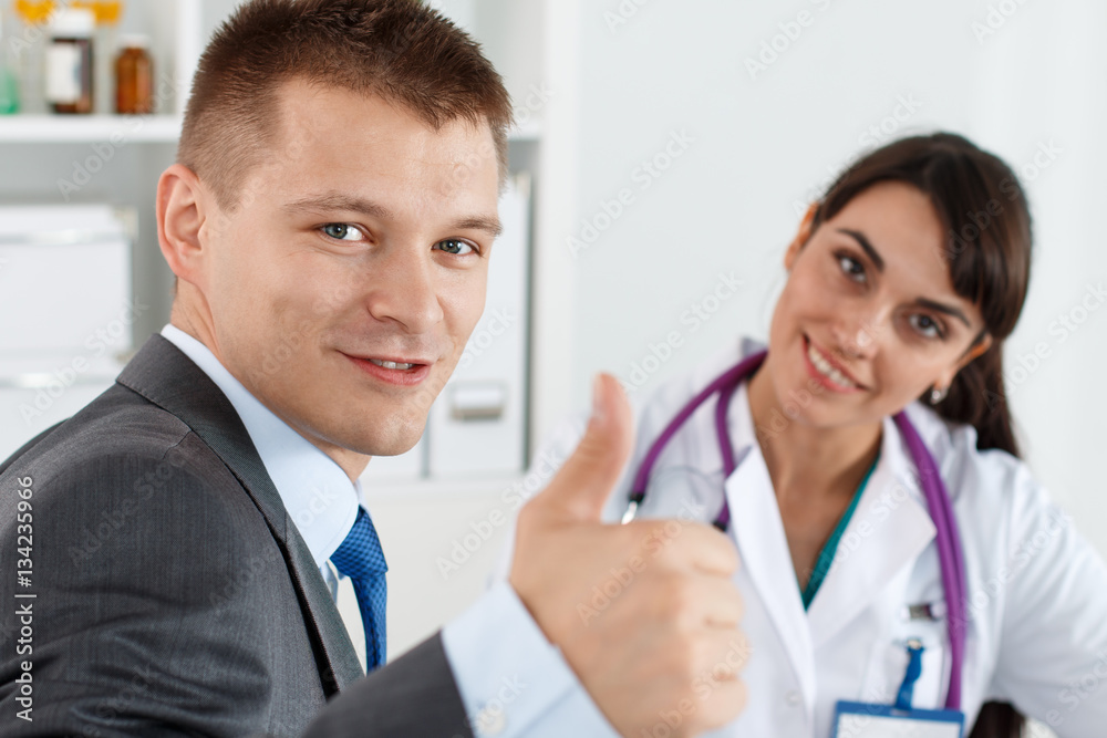 Smiling businessman in suit showing OK or approval sign Smiling businessman in suit showing OK or approval sign