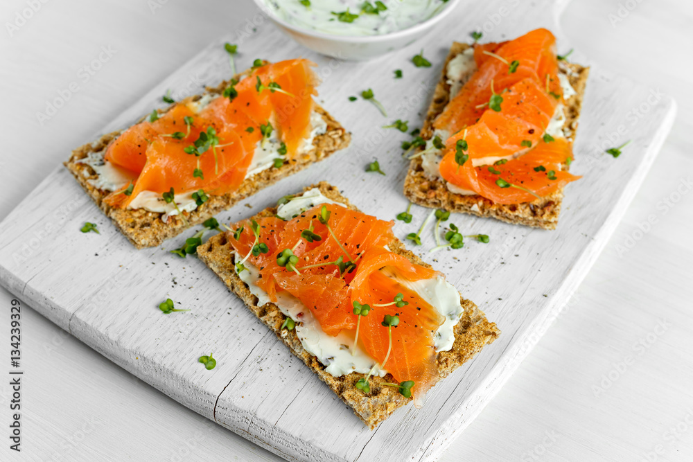 Homemade Crispbread toast with Smoked Salmon, Melted Cheese and cress salad. on white wooden board Homemade Crispbread toast with Smoked Salmon, Melted Cheese and cress salad. on white wooden board