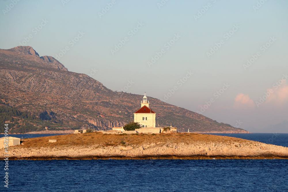 Picturesque lighthouse on a small island in the Adriatic Sea during sunset. Near town Hvar, island Hvar, Croatia. 