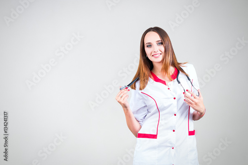 Smiling female doctor posing with lab coat and stethoscope isola