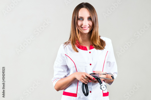 Smilling Female doctor standing in a robe and holding a stethosc photo