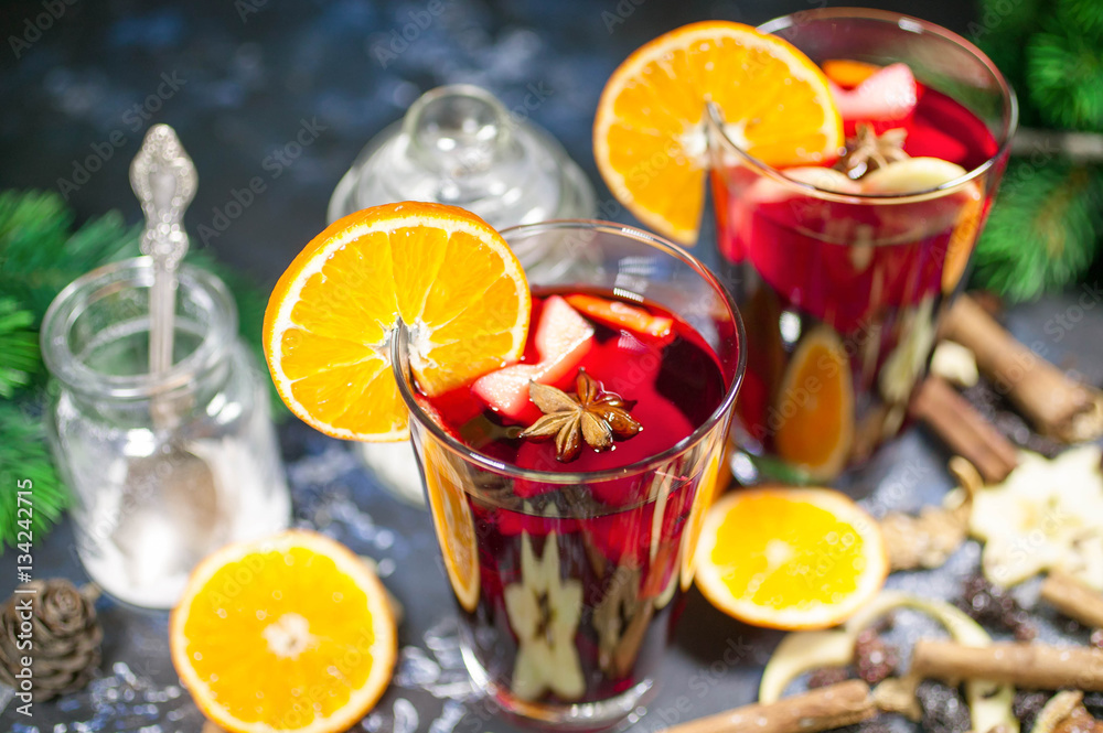 mulled wine on a dark stone table-top. fruit, spices, cinnamon and two glasses with drink
