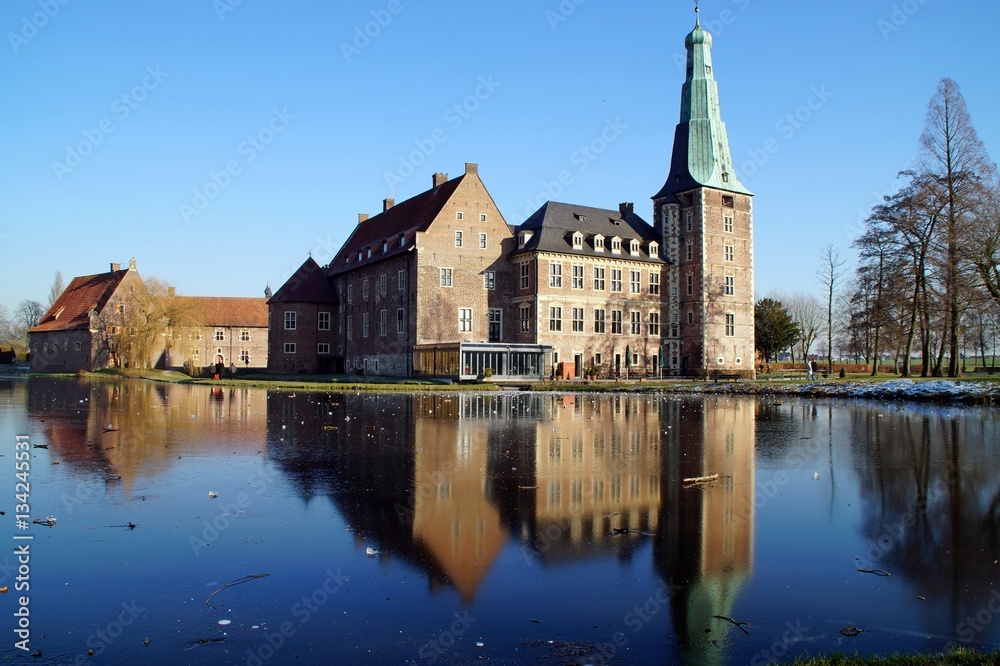 Fototapeta premium Schloss Raesfeld mit Spiegelung im zugefrorenen Wassergraben.