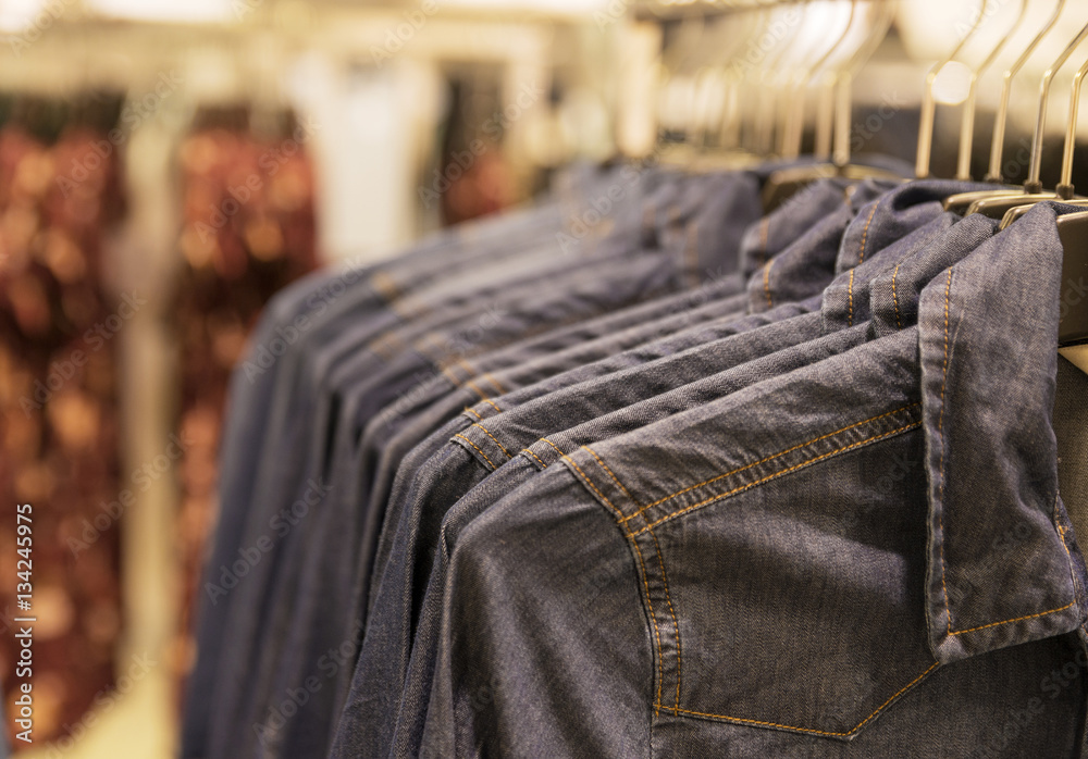 Fototapeta premium Shirts on metal hangers hang in a row