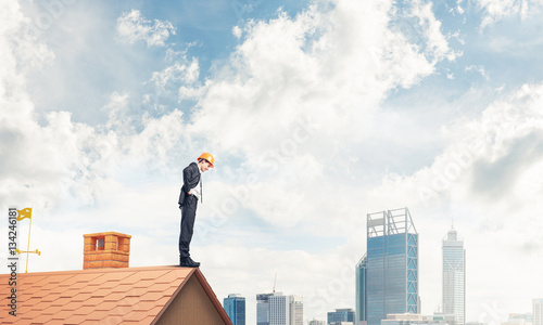 Businessman looking down from roof and modern cityscape at backgound