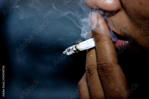 Принти на полотні The man use fingers holding a cigarette and smokes close up