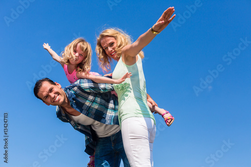 Father, mother and daughter playing plane