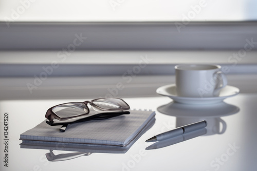 Table next to the window with a notebook and glasses