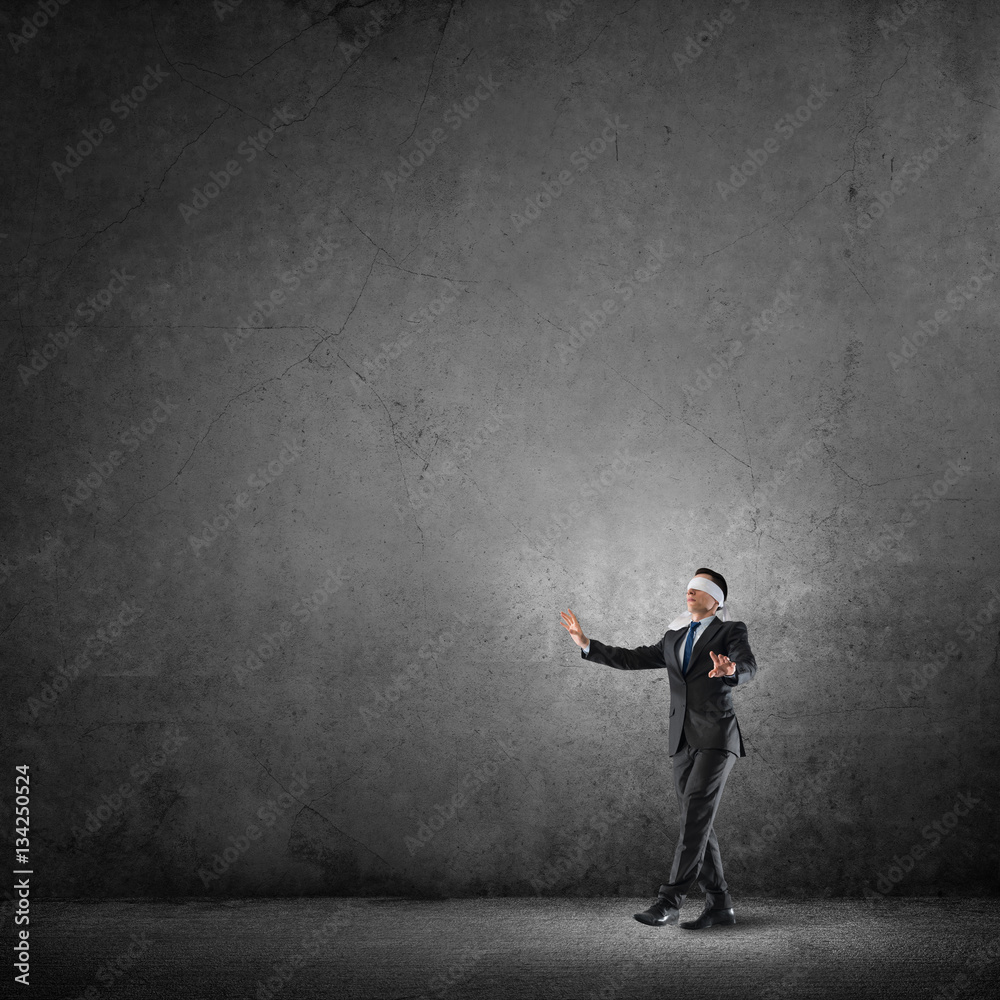 Business concept of risk with businessman wearing blindfold in empty concrete room Business concept of risk with businessman wearing blindfold in empty concrete room
